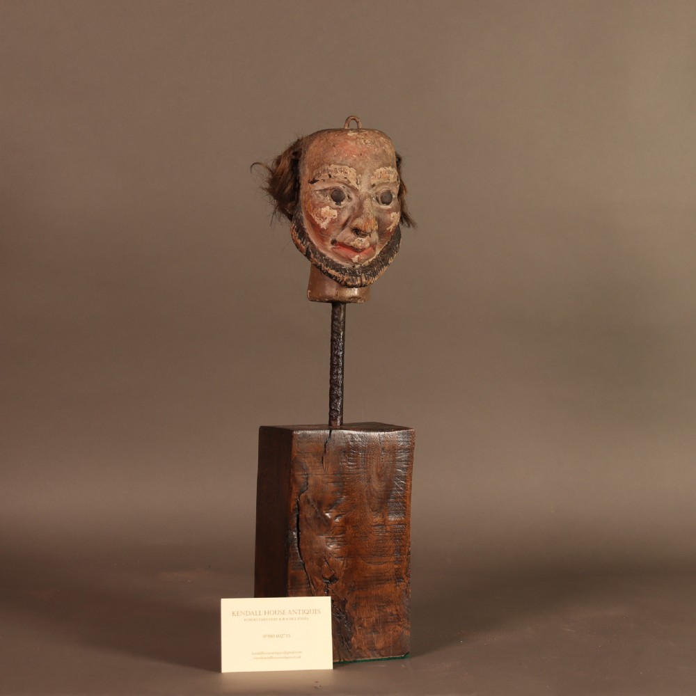 A nineteenth-century carved and polychrome painted wooden puppet head featuring natural hair and a bearded face, displayed on a metal stand. View VI