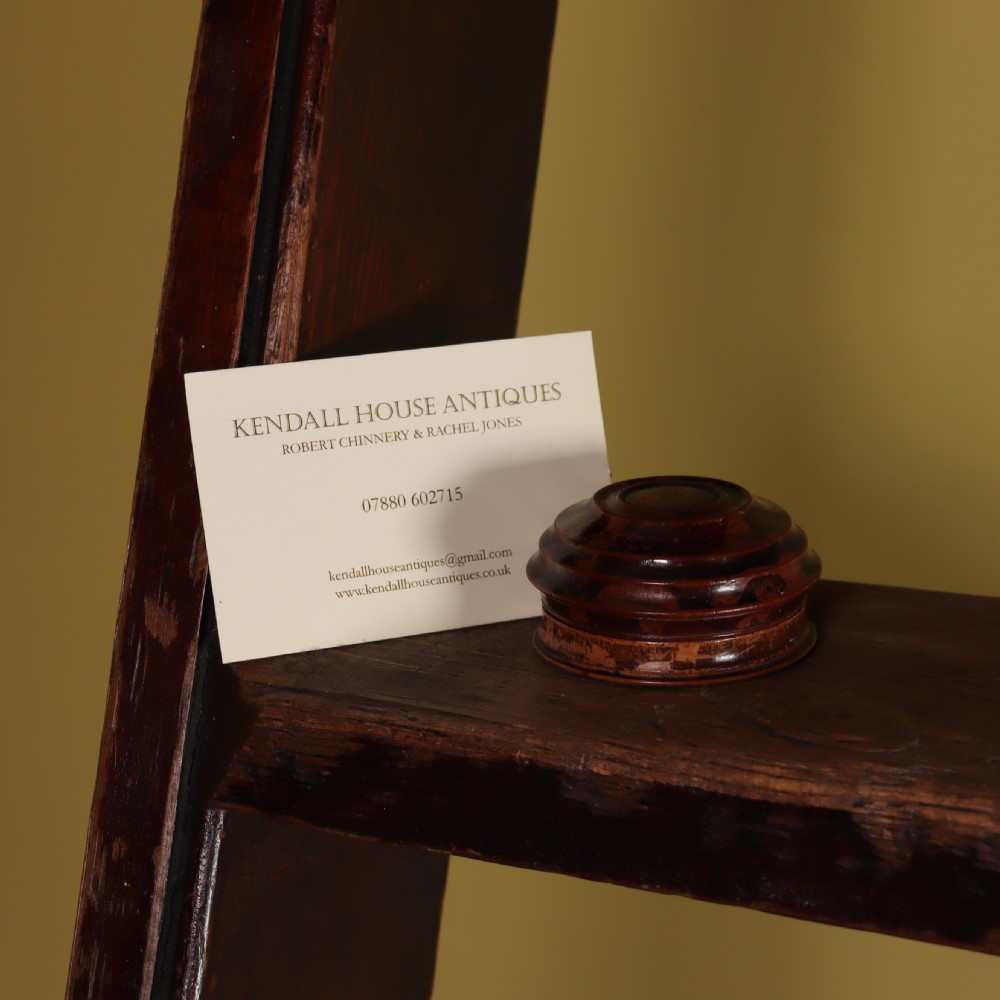 An open circular turned wood case displaying a Georgian magnetic pocket sundial with a pink printed makers label inside the lid. View III
