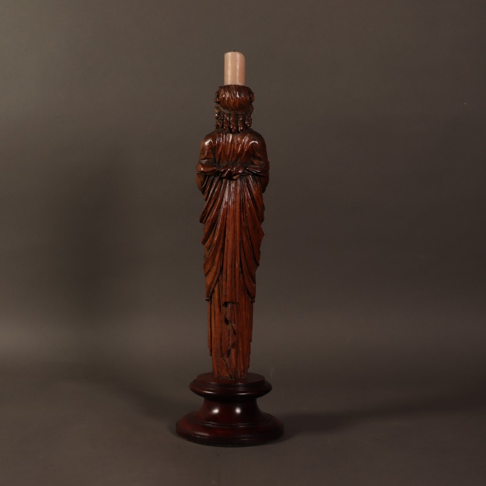 A 19th-century carved wooden candlestick shaped as a draped female figure standing on a round turned socle base. View IV
