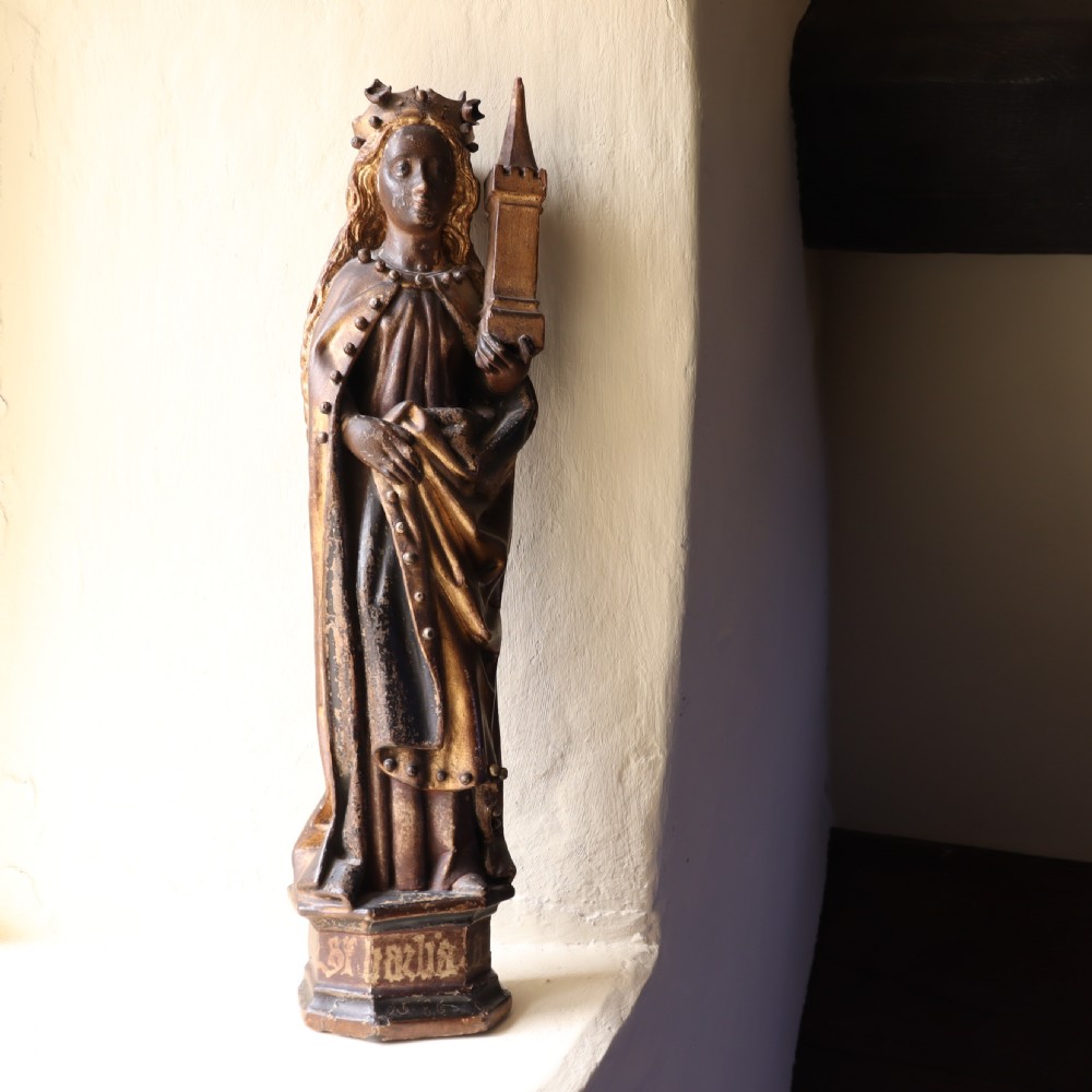 A 17th-century German carved polychrome and giltwood sculpture depicting Saint Barbara holding a tower, standing upon an inscribed plinth. View II