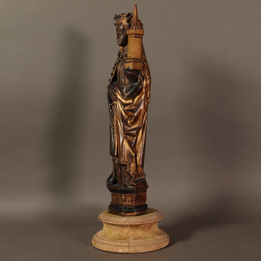 A 17th-century German carved polychrome and giltwood sculpture depicting Saint Barbara holding a tower, standing upon an inscribed plinth. View IV