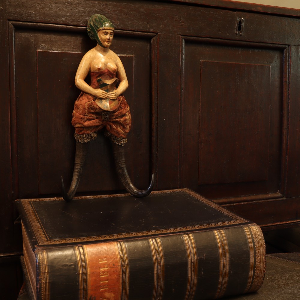 A 19th-century carved wood and horn wall hook featuring a polychrome figure of a female torso above curved dark horns forming the hooks. View II