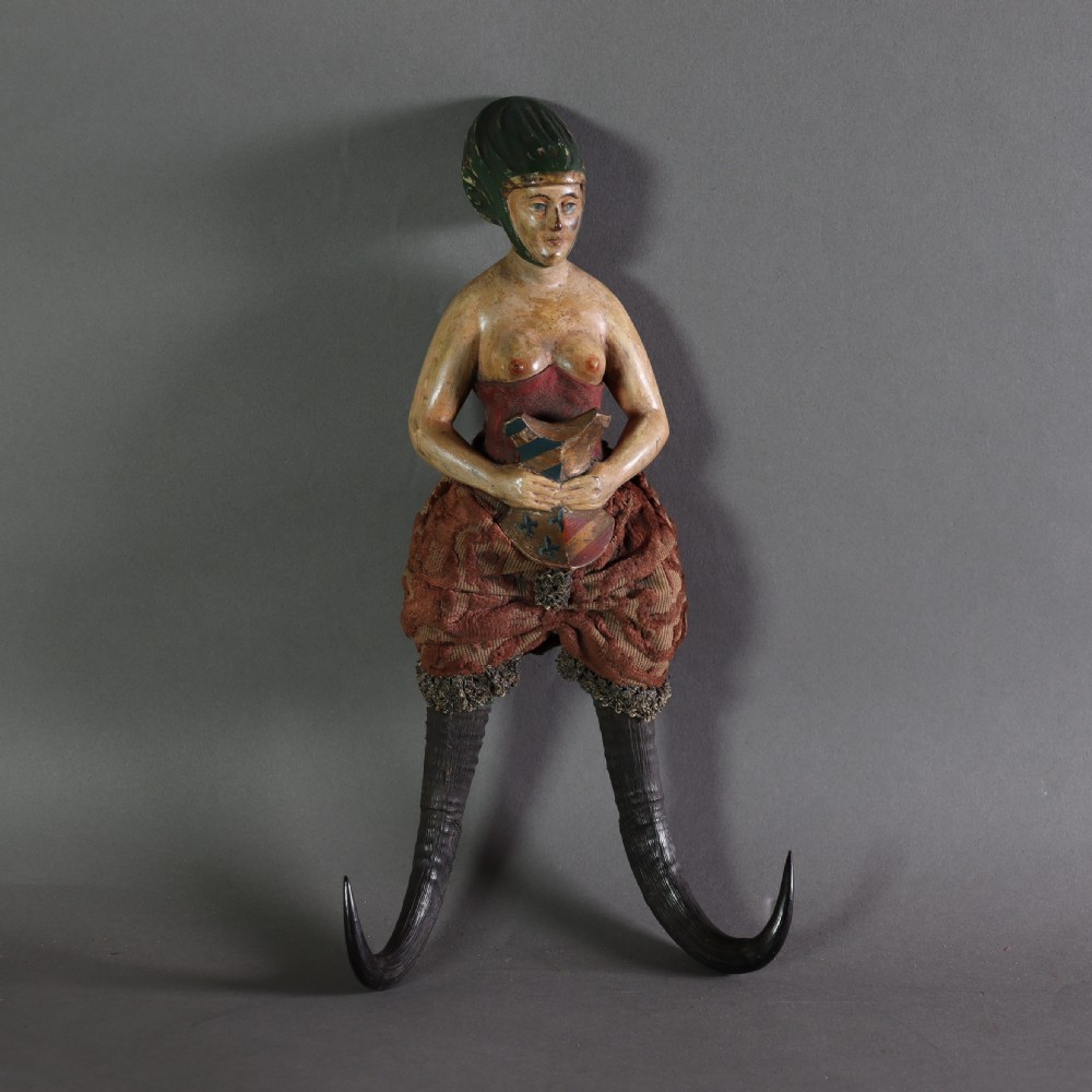 A 19th-century carved wood and horn wall hook featuring a polychrome figure of a female torso above curved dark horns forming the hooks.