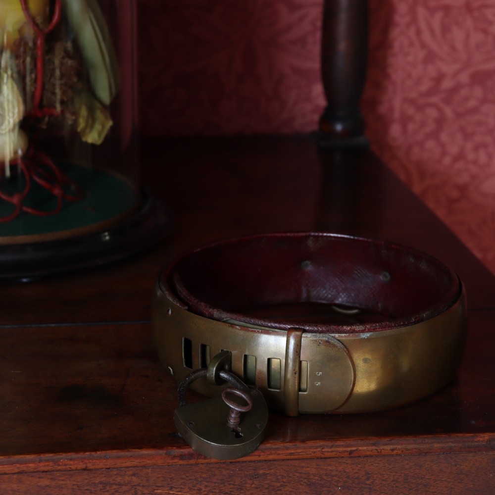 A heavy early nineteenth century bevelled brass dog collar lined with red leather and secured with a brass padlock and key. View IV