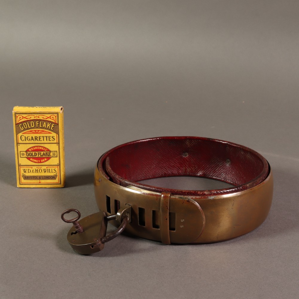A heavy early nineteenth century bevelled brass dog collar lined with red leather and secured with a brass padlock and key. View VII