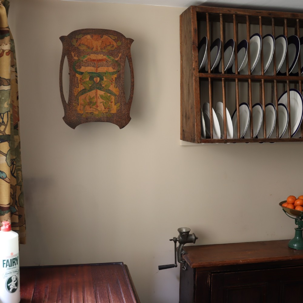 An Arts and Crafts wooden wall cupboard decorated with pyrography and painted motifs depicting an owl, green serpents, and foliage against a dark textured surface. View IV