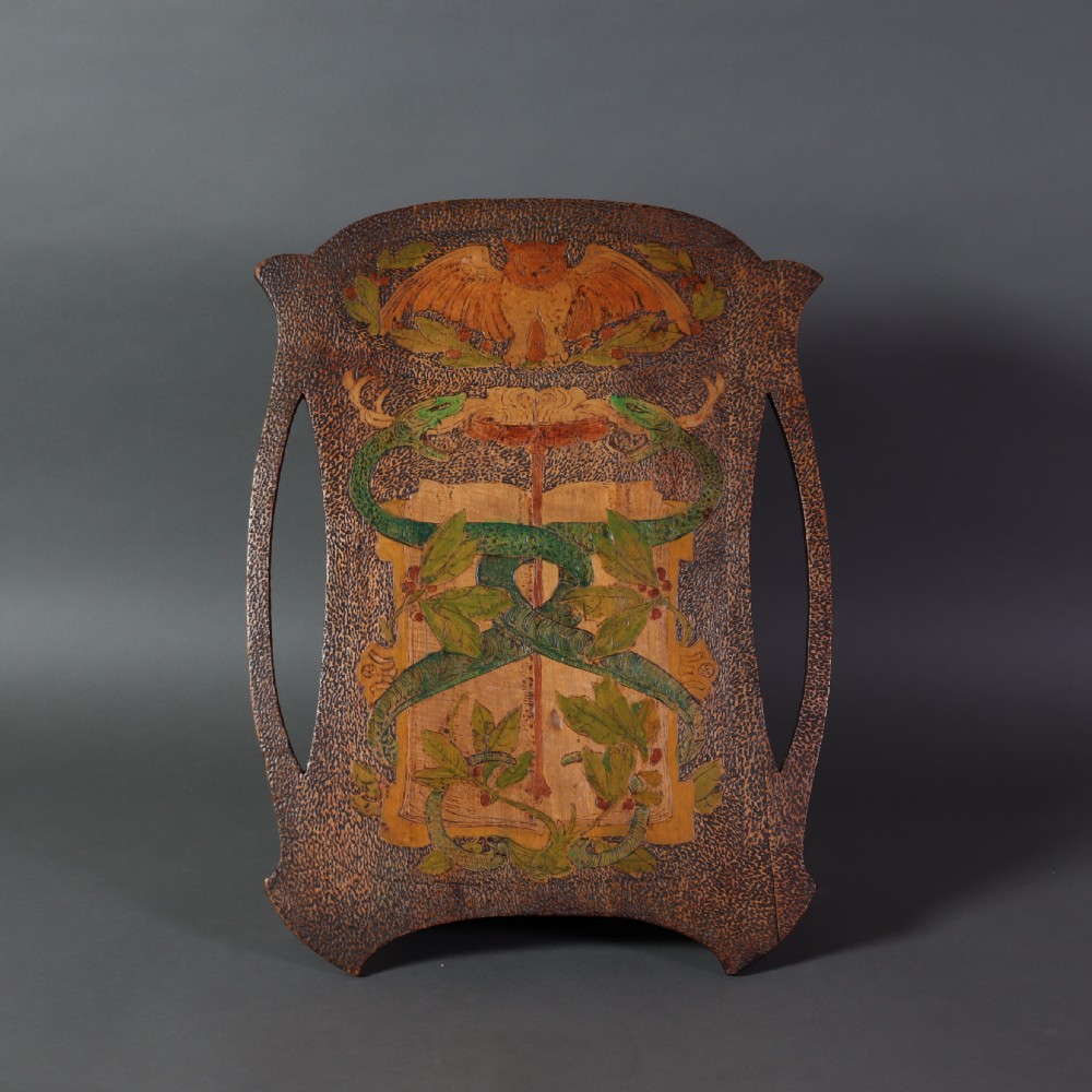 An Arts and Crafts wooden wall cupboard decorated with pyrography and painted motifs depicting an owl, green serpents, and foliage against a dark textured surface.