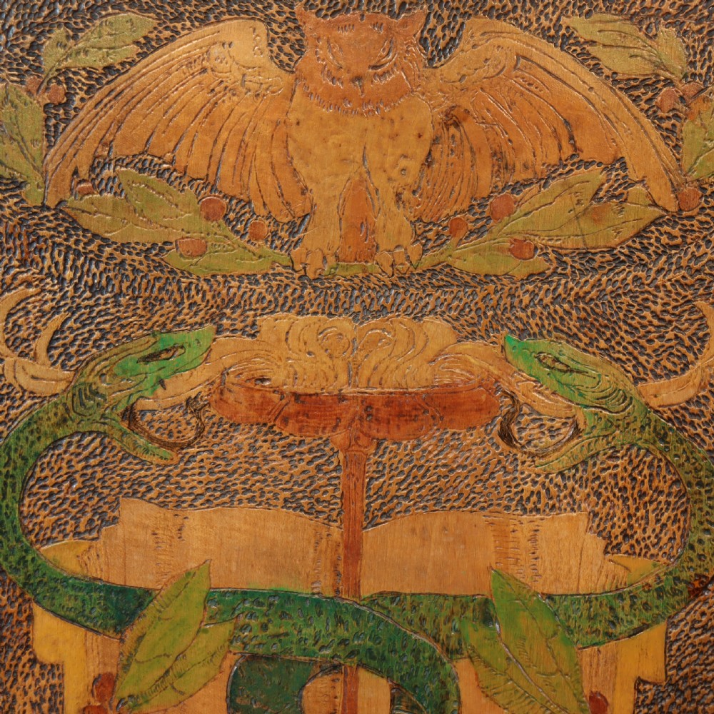 An Arts and Crafts wooden wall cupboard decorated with pyrography and painted motifs depicting an owl, green serpents, and foliage against a dark textured surface. View VIII