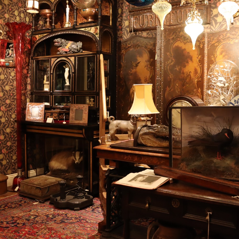 An Aesthetic Movement ebonised mahogany display cabinet featuring gilt highlights, turned spindle arcades, painted floral panels, and mirrored doors. View III