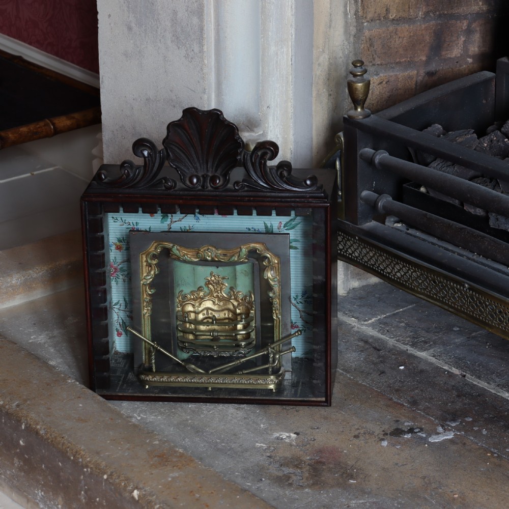 A Victorian miniature fireplace model with brass and iron hearth details, enclosed in a dark wood cabinet with a shell carved pediment. View II