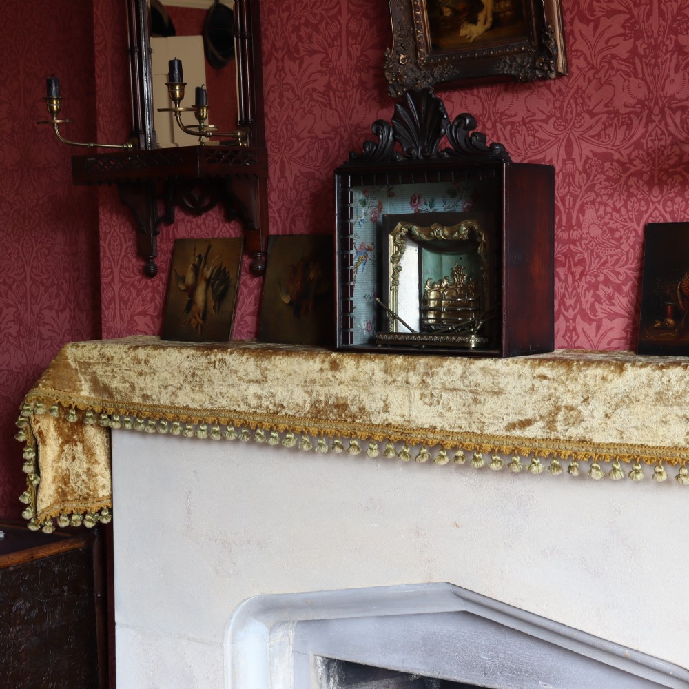 A Victorian miniature fireplace model with brass and iron hearth details, enclosed in a dark wood cabinet with a shell carved pediment. View VI