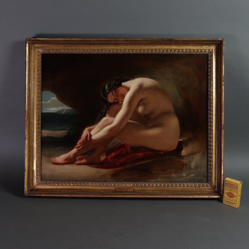 An antique oil painting on wood panel depicting a seated female nude inside a dark cave facing a seascape, set within a gilded molded frame. View VI