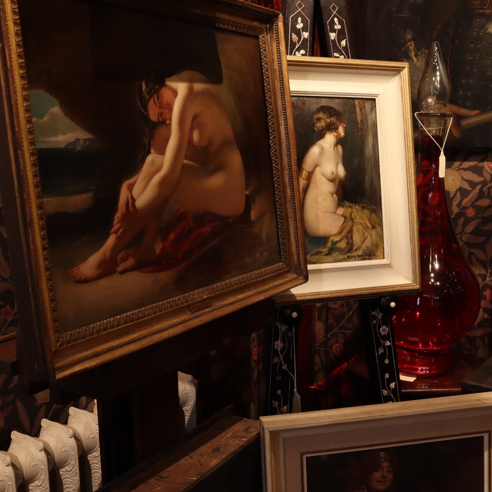 An antique oil painting on wood panel depicting a seated female nude inside a dark cave facing a seascape, set within a gilded molded frame. View IX