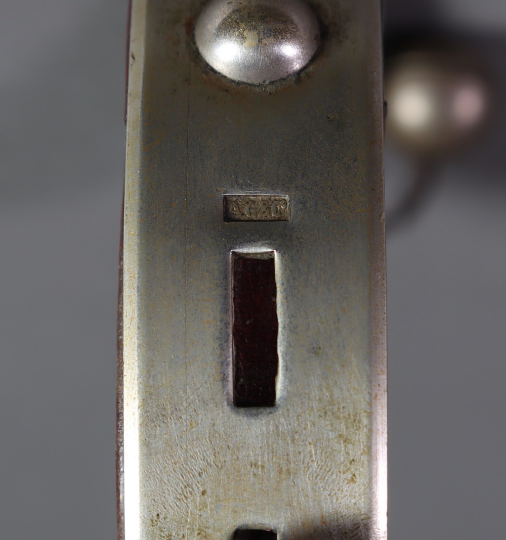 An Edwardian white metal dog collar featuring a brown leather lining, raised metal studs, an attached brass bell, and a functional padlock with key. View VI