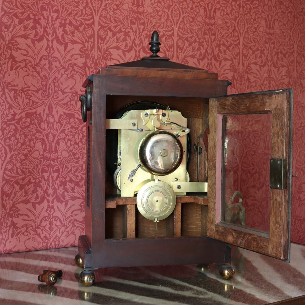 A George IV mahogany bracket clock featuring ebony inlaid lines, brass ball feet, side carrying handles, and a circular white dial signed by L. Vick of Stroud. View VI