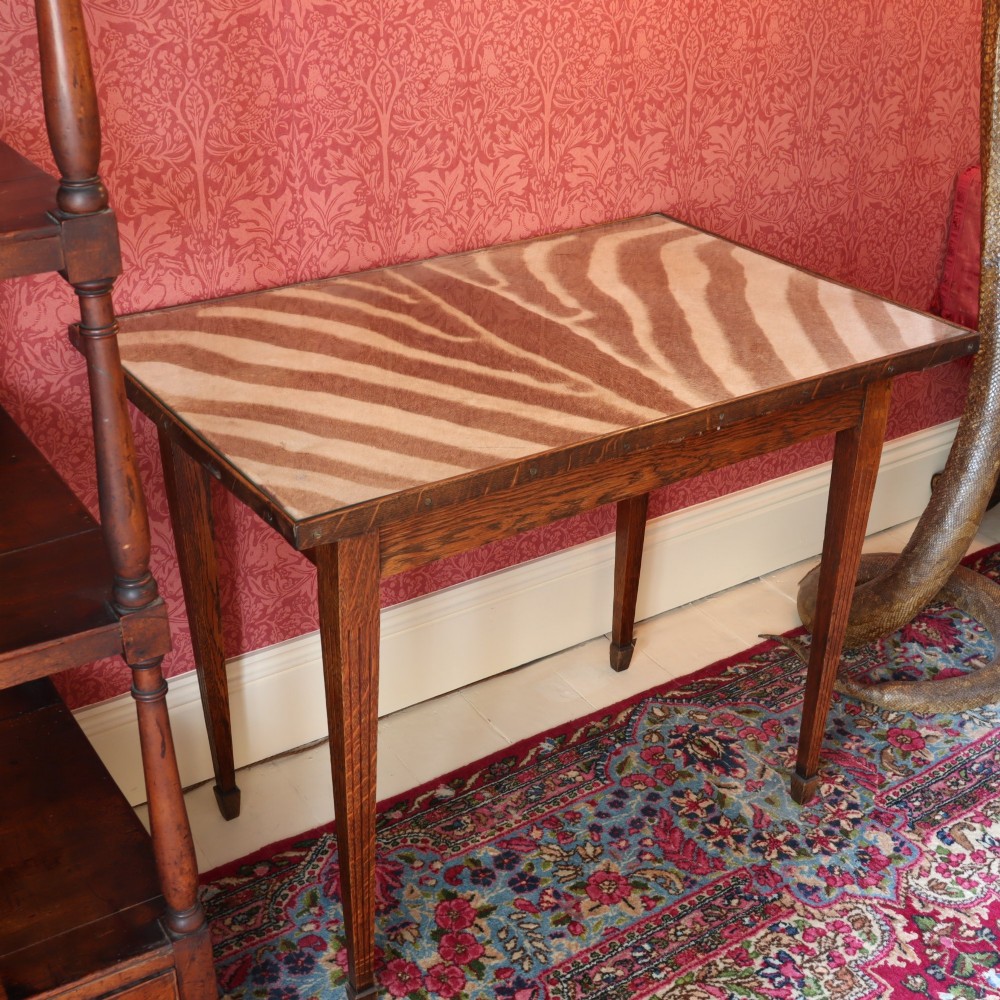A rectangular oak occasional table featuring a zebra hide inset top protected by glass, supported by four tapered square legs.
