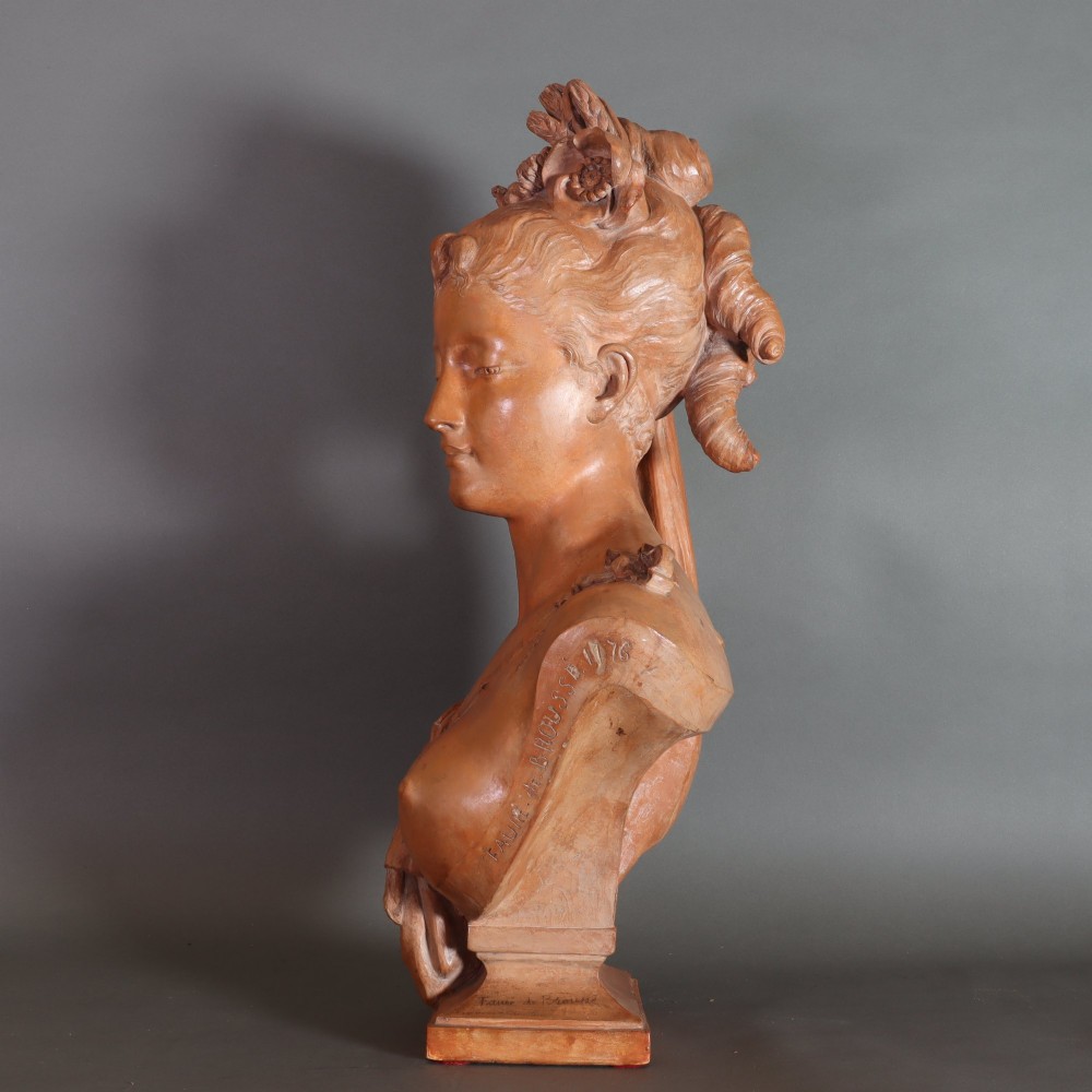 A Neoclassical terracotta bust depicting a young woman with a floral hair arrangement and draped semi-nude torso set on an integrated base. View VII