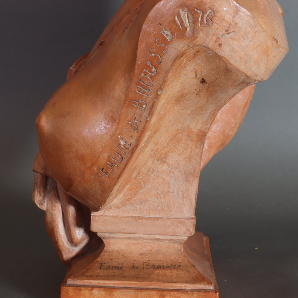 A Neoclassical terracotta bust depicting a young woman with a floral hair arrangement and draped semi-nude torso set on an integrated base. View VIII