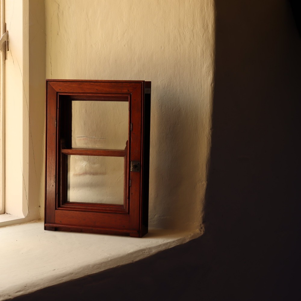 A 19th-century miniature mahogany sash window model featuring glazed panes and a polished timber frame.