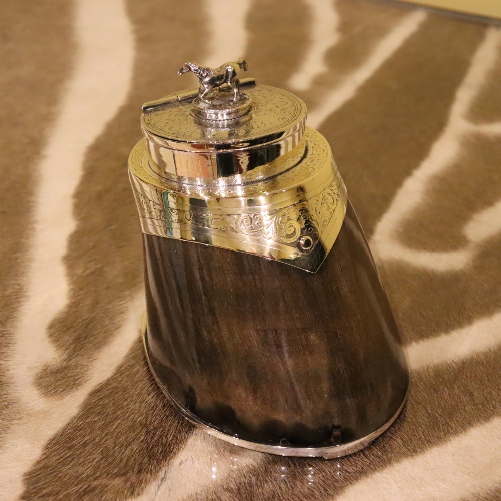 A Victorian desk tidy crafted from a preserved horse hoof with engraved silver mounts and a lid featuring a sculpted horse figurine.