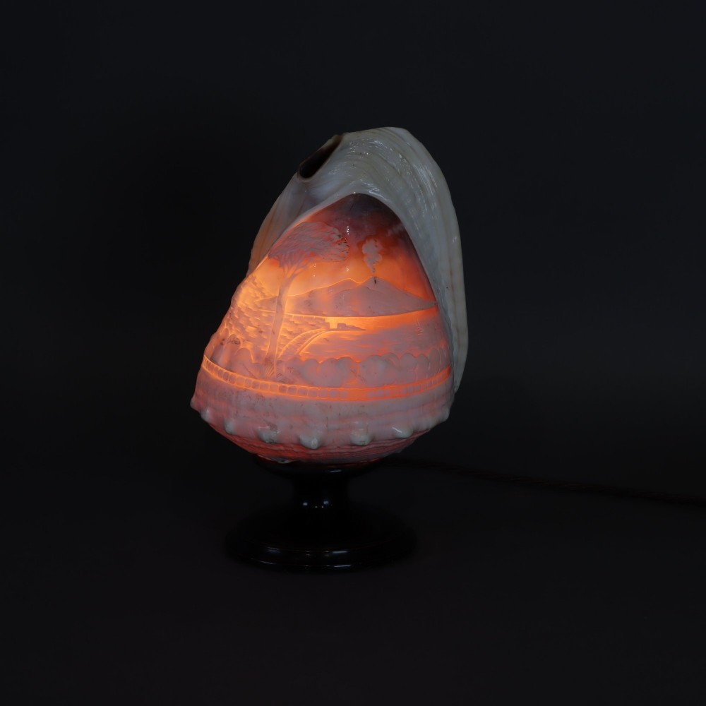 An illuminated 19th-century conch shell carved in relief with a scene depicting Mount Vesuvius, mounted on a turned ebonised wood base. View IV