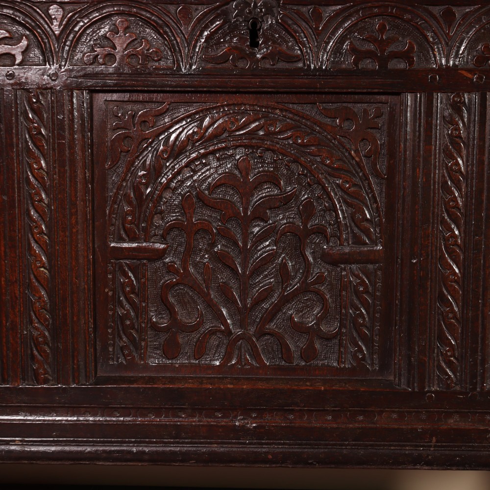 A mid-17th-century dark oak panelled coffer with three carved arch panels and a detailed frieze. View IV