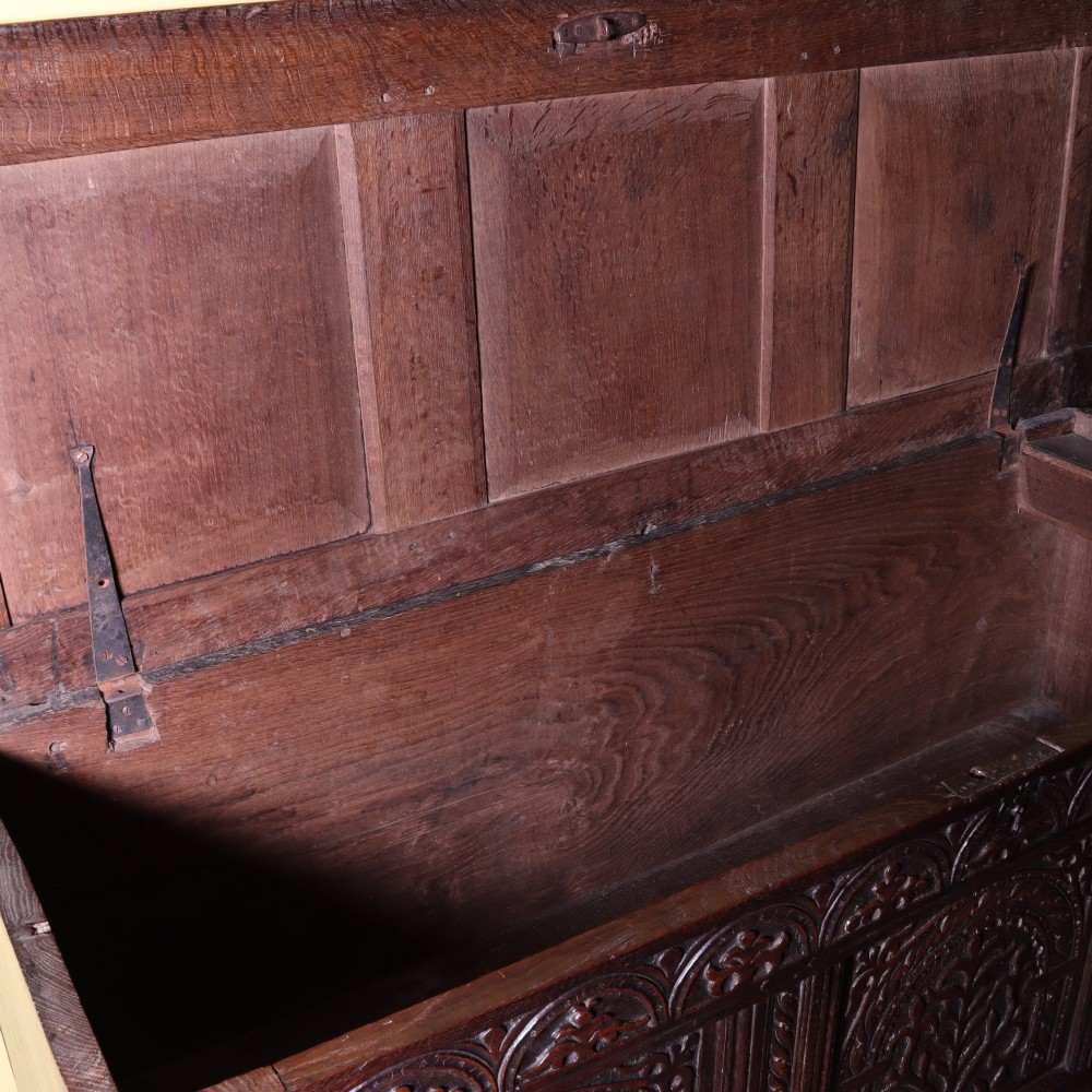 A mid-17th-century dark oak panelled coffer with three carved arch panels and a detailed frieze. View V