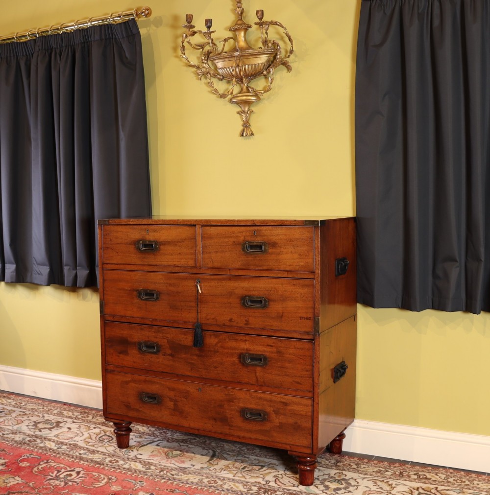 A Victorian mahogany two-part military campaign chest of drawers featuring recessed brass handles, corner brackets, side carrying handles, and short turned feet.