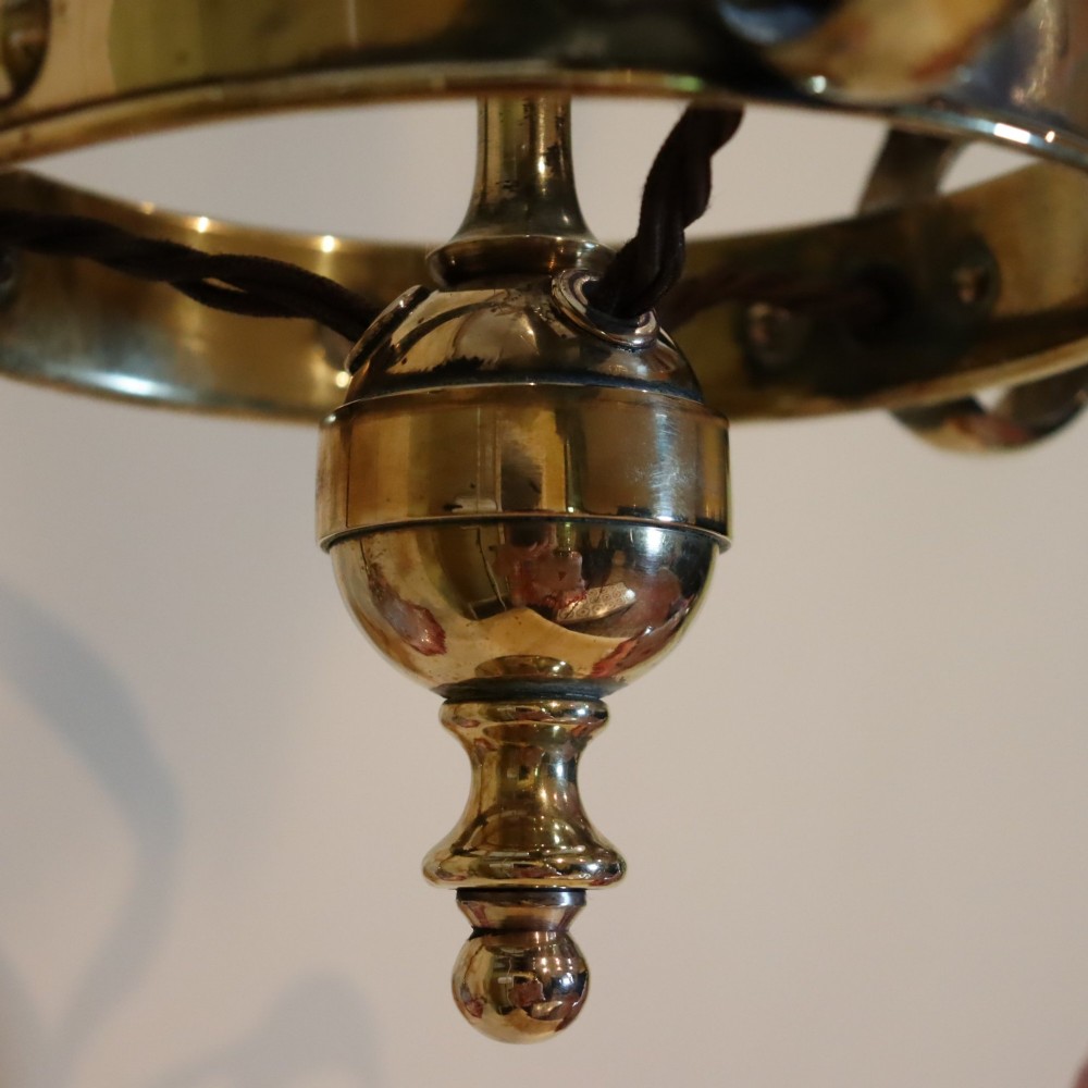 An Arts and Crafts brass ceiling light featuring three curved arms holding ruffled cranberry glass shades with painted floral motifs. View VII