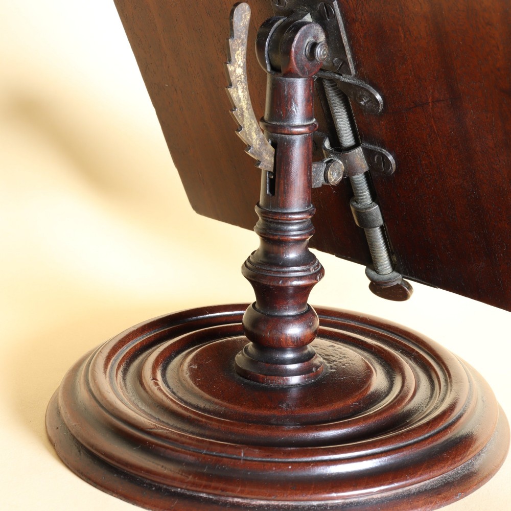A 19th-century dark mahogany desktop reading stand featuring an upright wooden backplate, metal page retainers, and a moulded circular swivel base. View III