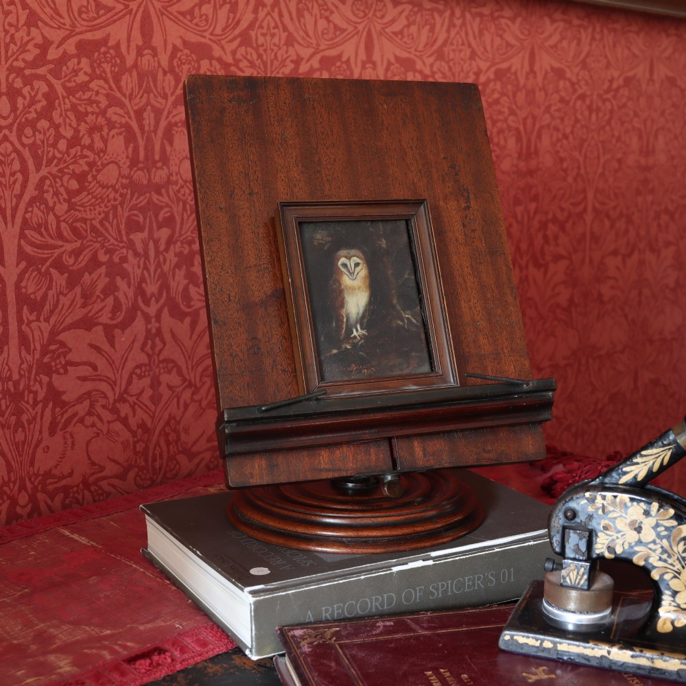 A 19th-century dark mahogany desktop reading stand featuring an upright wooden backplate, metal page retainers, and a moulded circular swivel base. View V