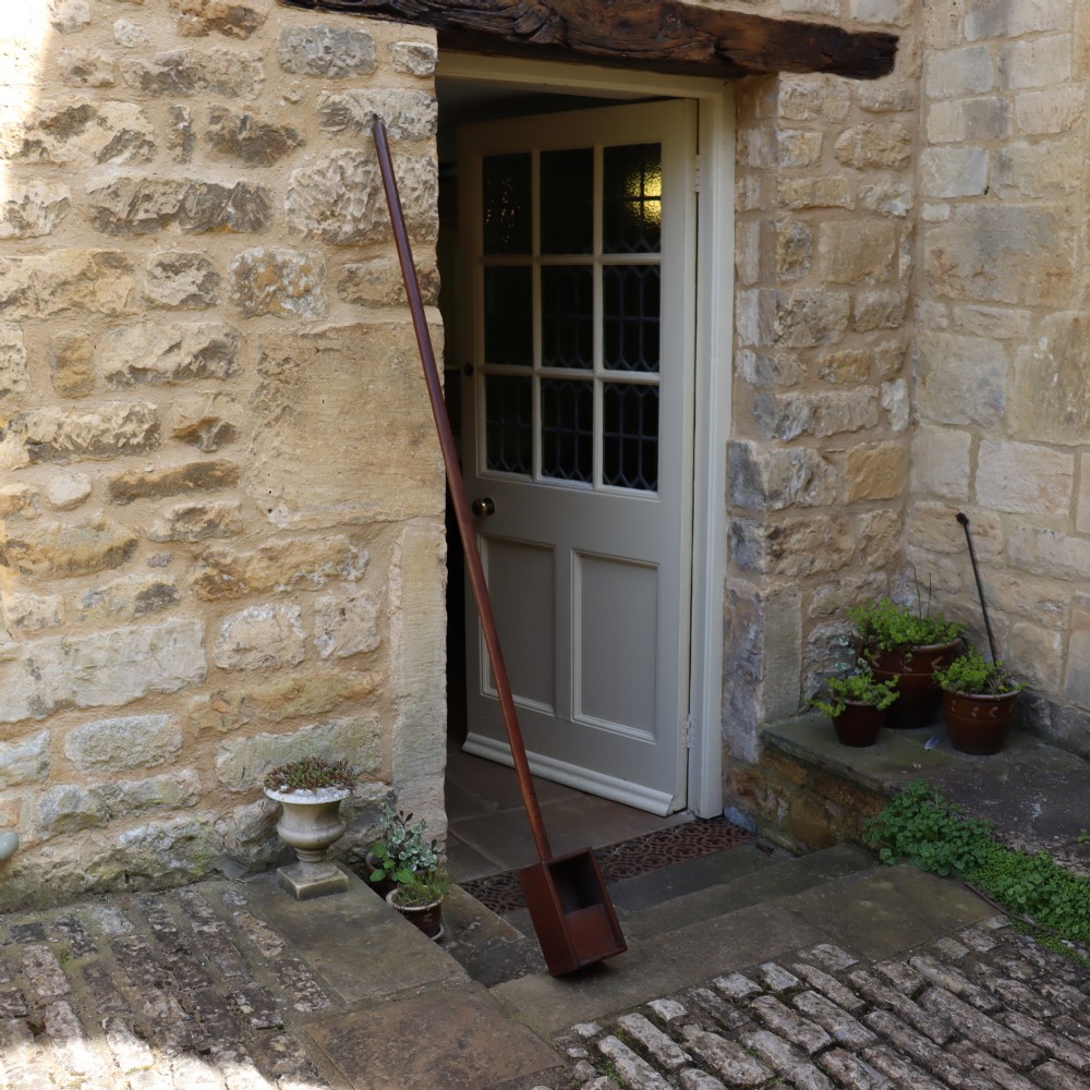 An antique long-handled dark wooden church collection box with a turned pole and a rectangular open container at the end. View IV