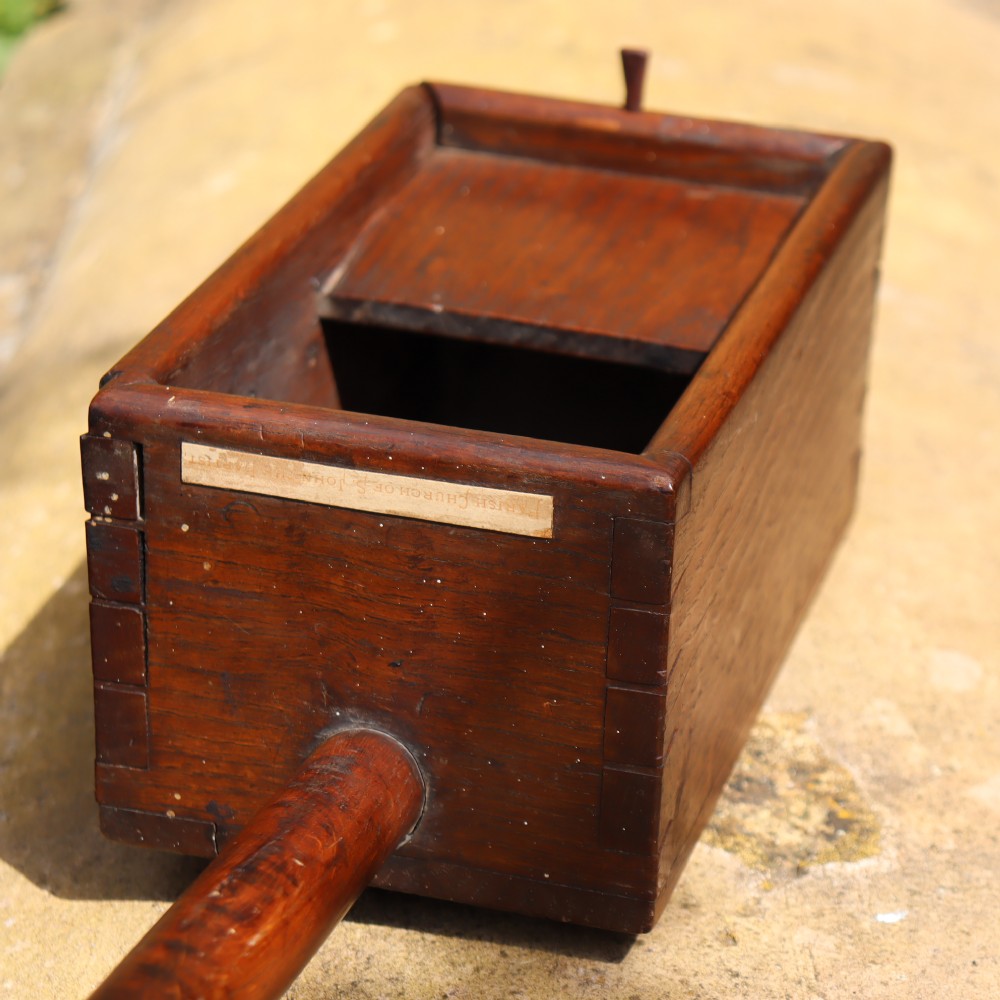 An antique long-handled dark wooden church collection box with a turned pole and a rectangular open container at the end. View VI