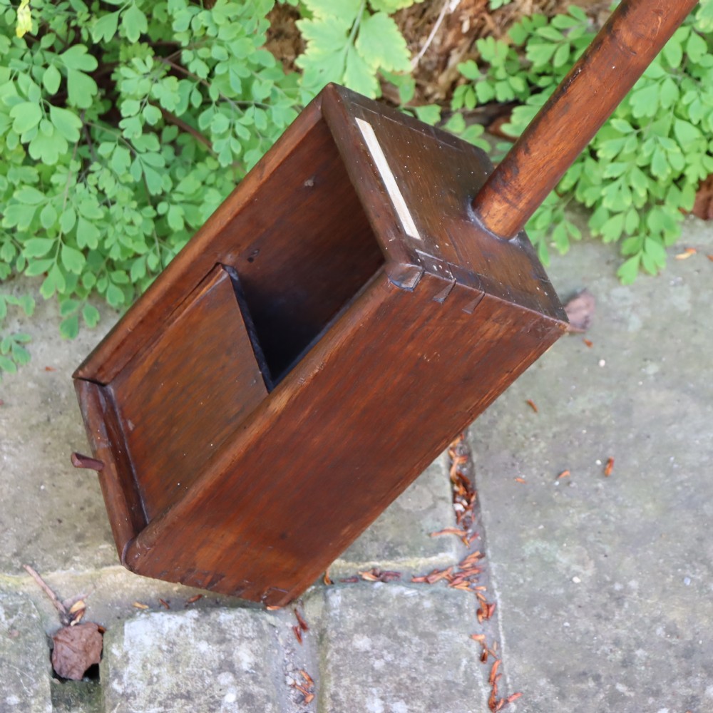 An antique long-handled dark wooden church collection box with a turned pole and a rectangular open container at the end. View VII