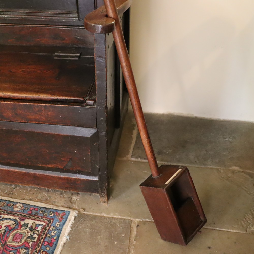 An antique long-handled dark wooden church collection box with a turned pole and a rectangular open container at the end. View IX