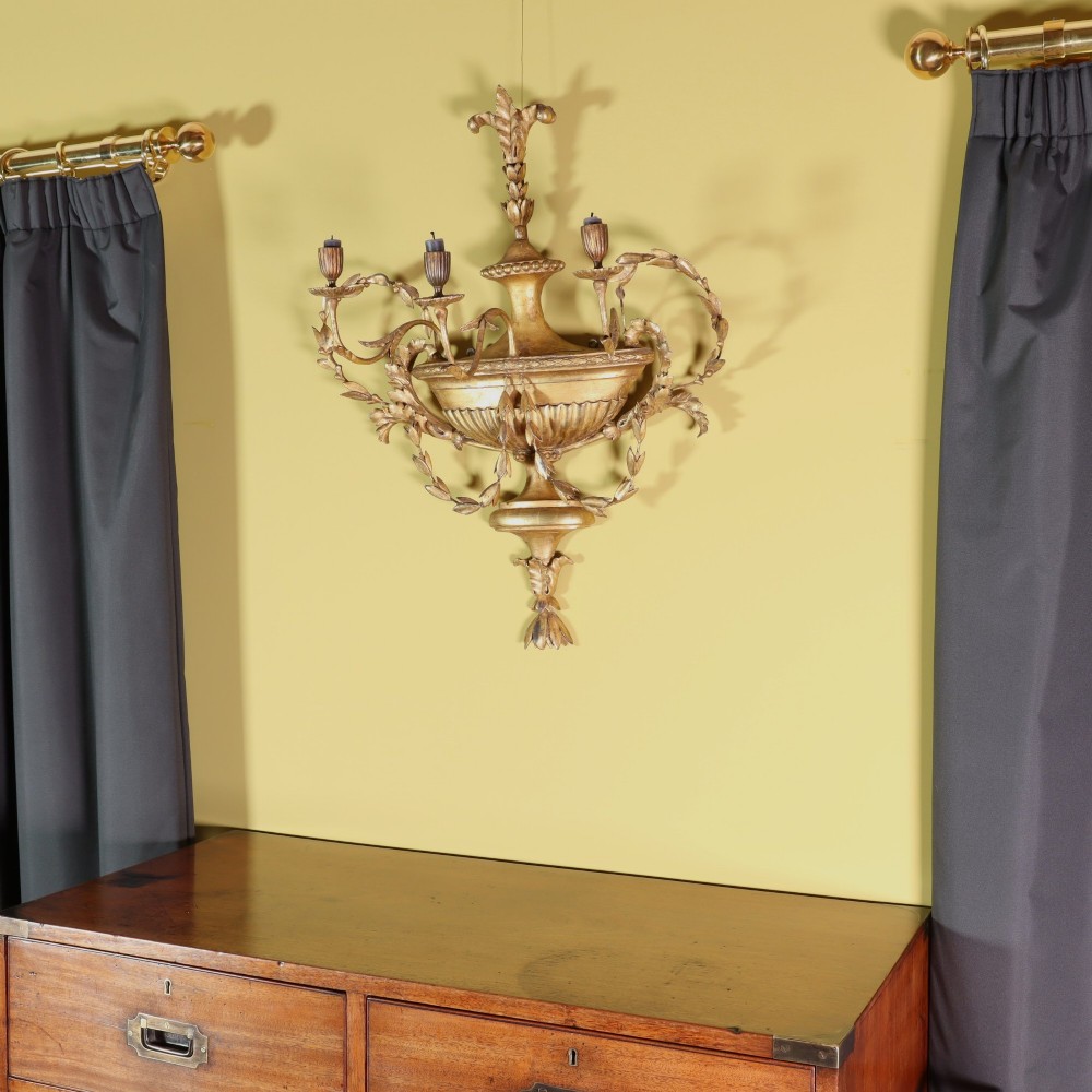 A George III style carved giltwood three-branch wall sconce featuring a central fluted urn motif flanked by scrolling foliate arms. View VII