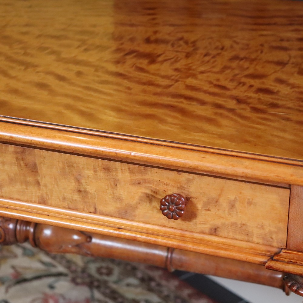 A Victorian satinwood side table featuring two frieze drawers with small round knobs, supported by carved trestle ends connected by a turned stretcher. View III