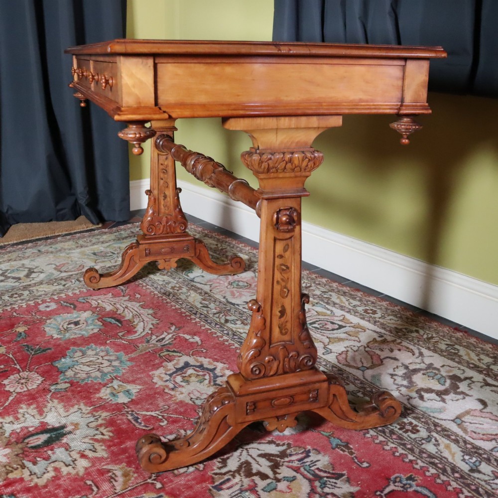 A Victorian satinwood side table featuring two frieze drawers with small round knobs, supported by carved trestle ends connected by a turned stretcher. View V