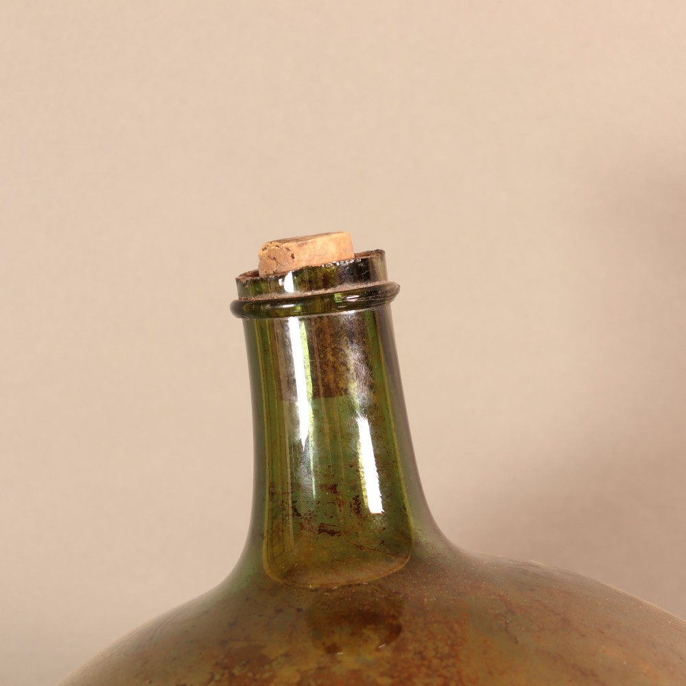 A large spherical olive green glass apothecary carboy featuring a painted banner with gilded scroll lettering. View V