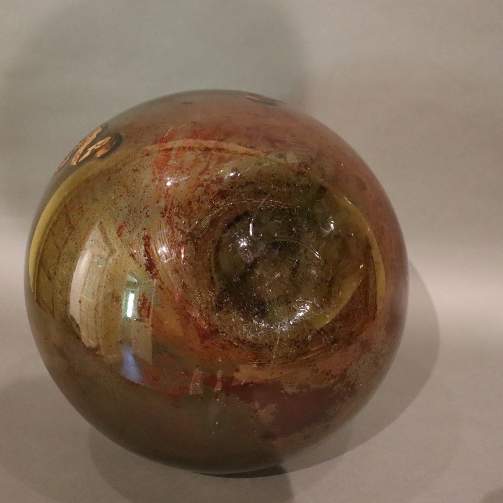 A large spherical olive green glass apothecary carboy featuring a painted banner with gilded scroll lettering. View VI
