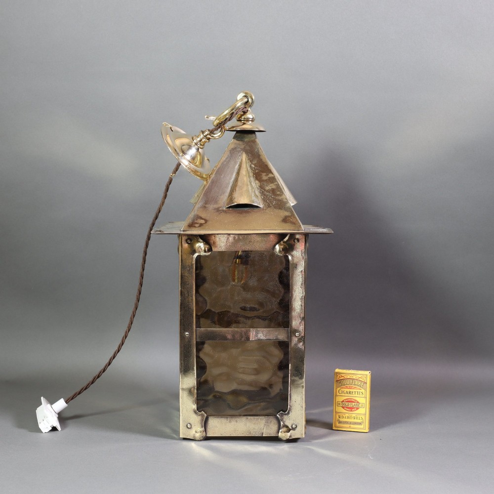 An Arts and Crafts style brass hanging lantern featuring amber textured glass panes, a riveted square body, a pyramidal top hood, and a ceiling chain suspension. View III
