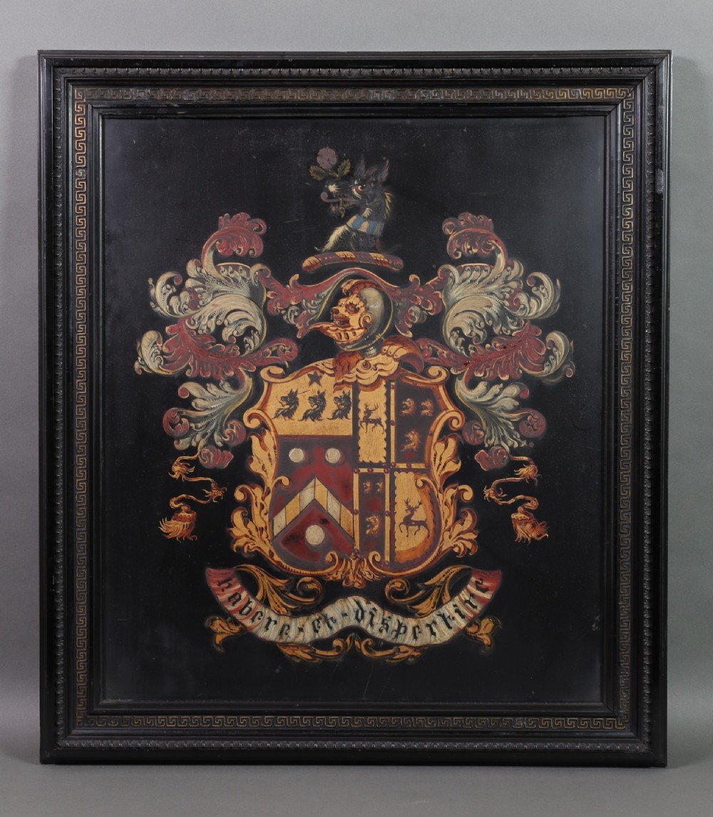 A large black-framed 19th-century panel featuring a painted coat of arms with red and cream mantling above a heraldic motto scroll. View II