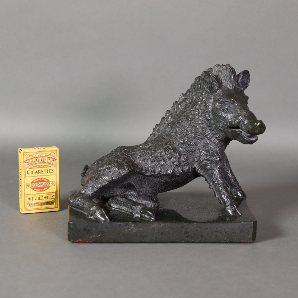 A late nineteenth-century Italian Grand Tour sculpture of a seated wild boar carved from dark green serpentine marble set on a rectangular stone plinth. View IX