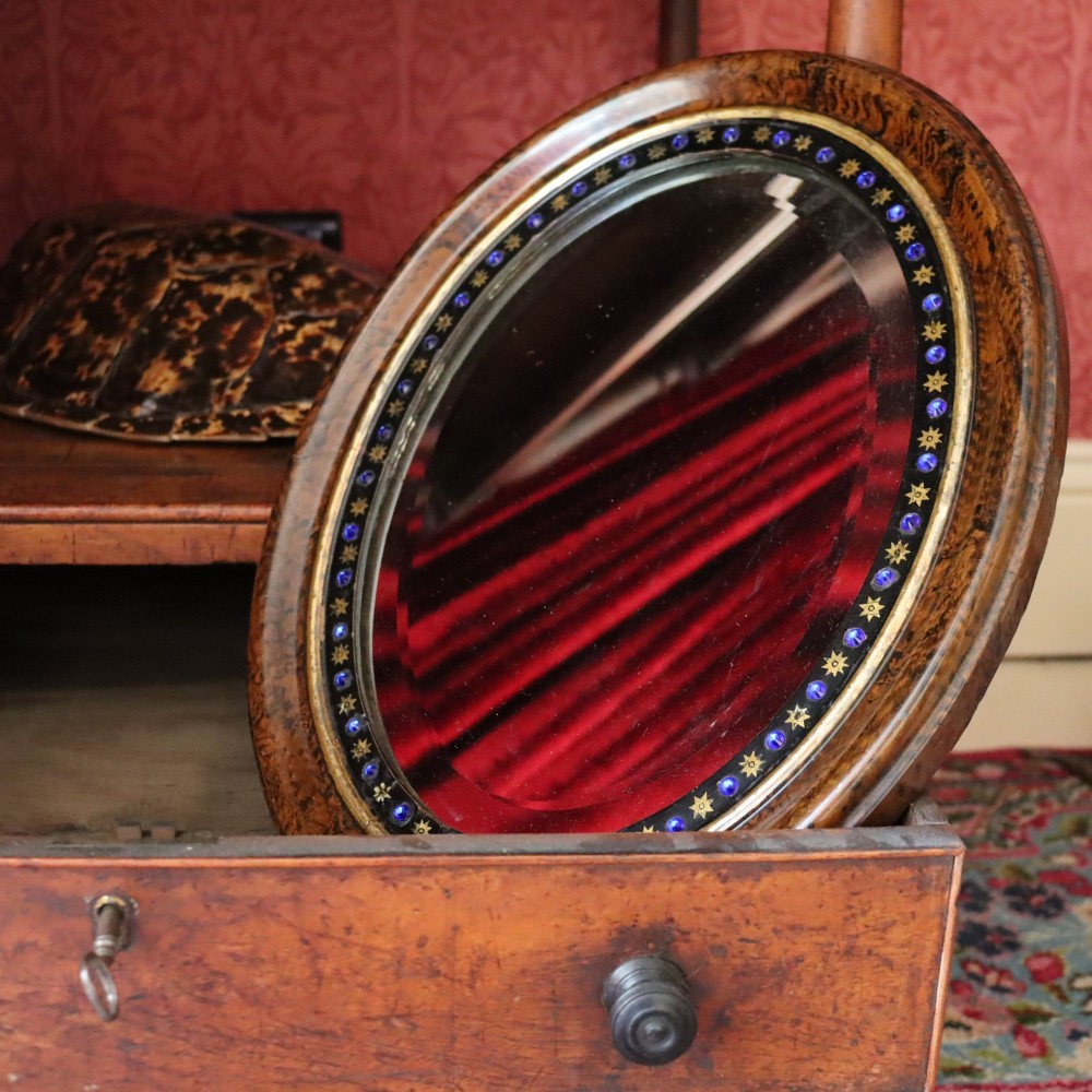 A late 19th-century oval wall mirror featuring a figured wood frame with an inner border of blue glass cabochons and gold star accents. View III