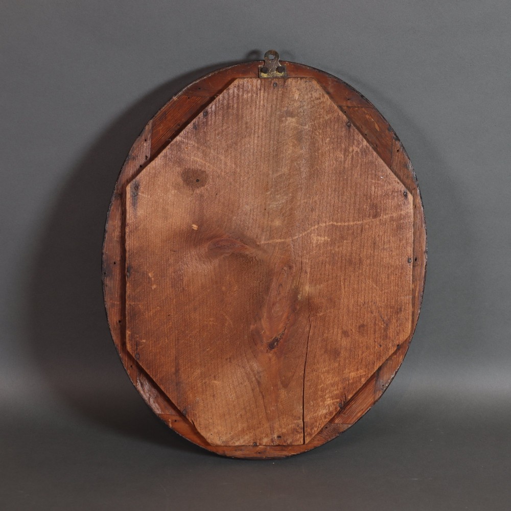 A late 19th-century oval wall mirror featuring a figured wood frame with an inner border of blue glass cabochons and gold star accents. View VII
