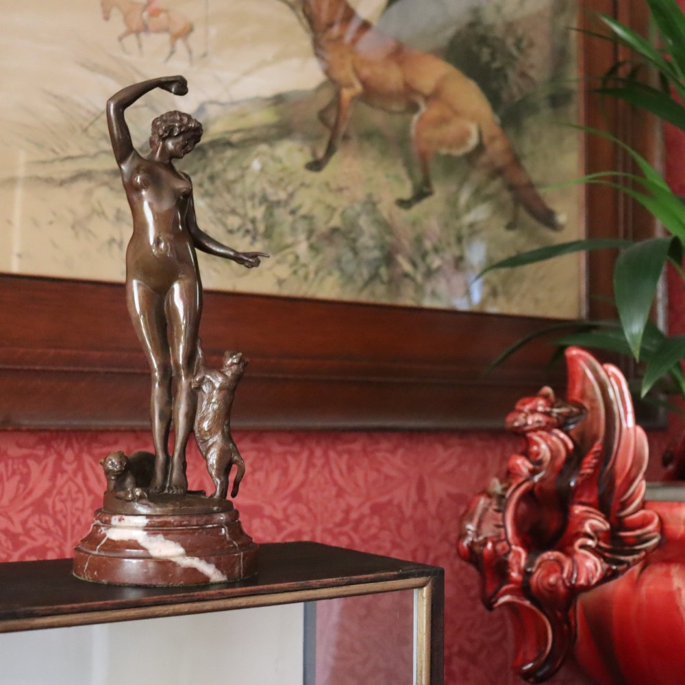 An Art Nouveau patinated bronze sculpture of a standing female figure with two cats mounted on a red marble base. View II