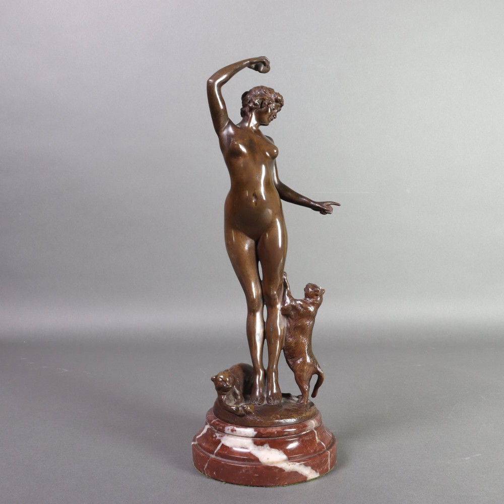 An Art Nouveau patinated bronze sculpture of a standing female figure with two cats mounted on a red marble base.