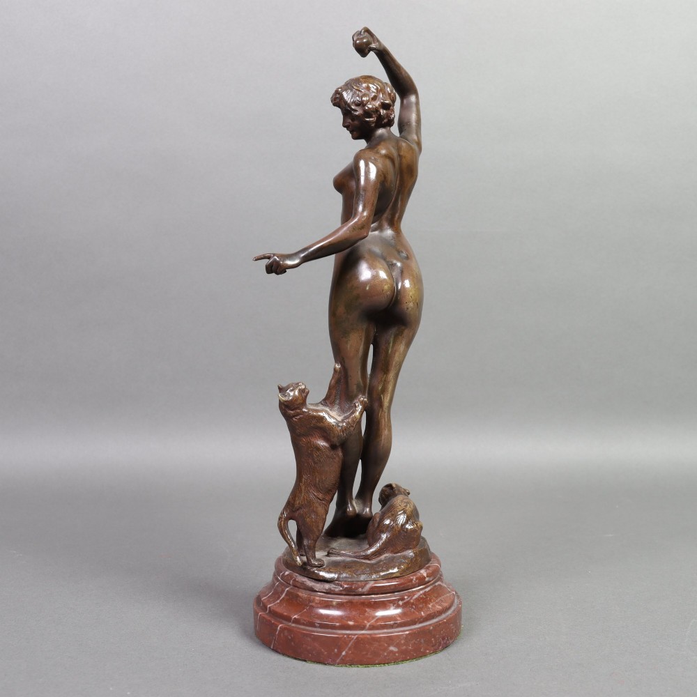 An Art Nouveau patinated bronze sculpture of a standing female figure with two cats mounted on a red marble base. View IX
