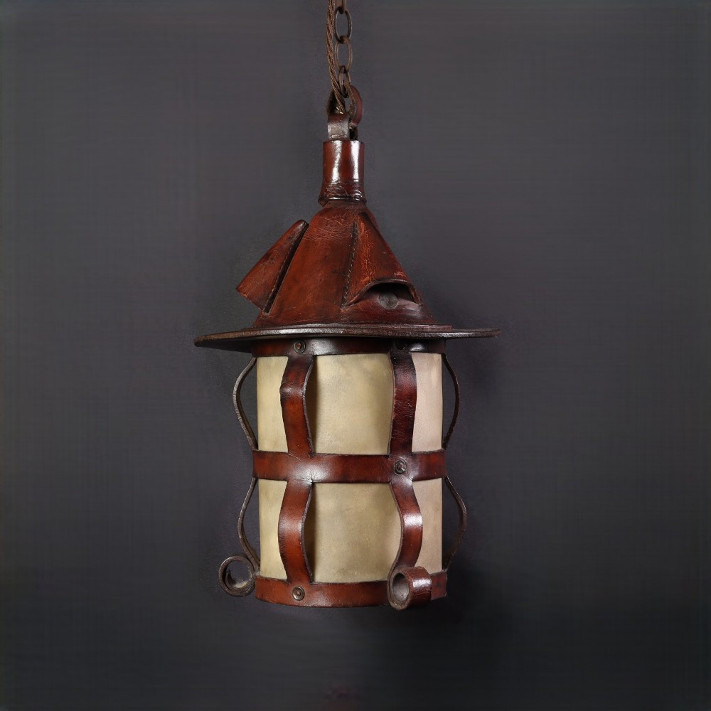 An Arts and Crafts hanging lantern featuring a hand-stitched dark brown leather framework surrounding illuminated vellum panels with scrolled metal feet. View II