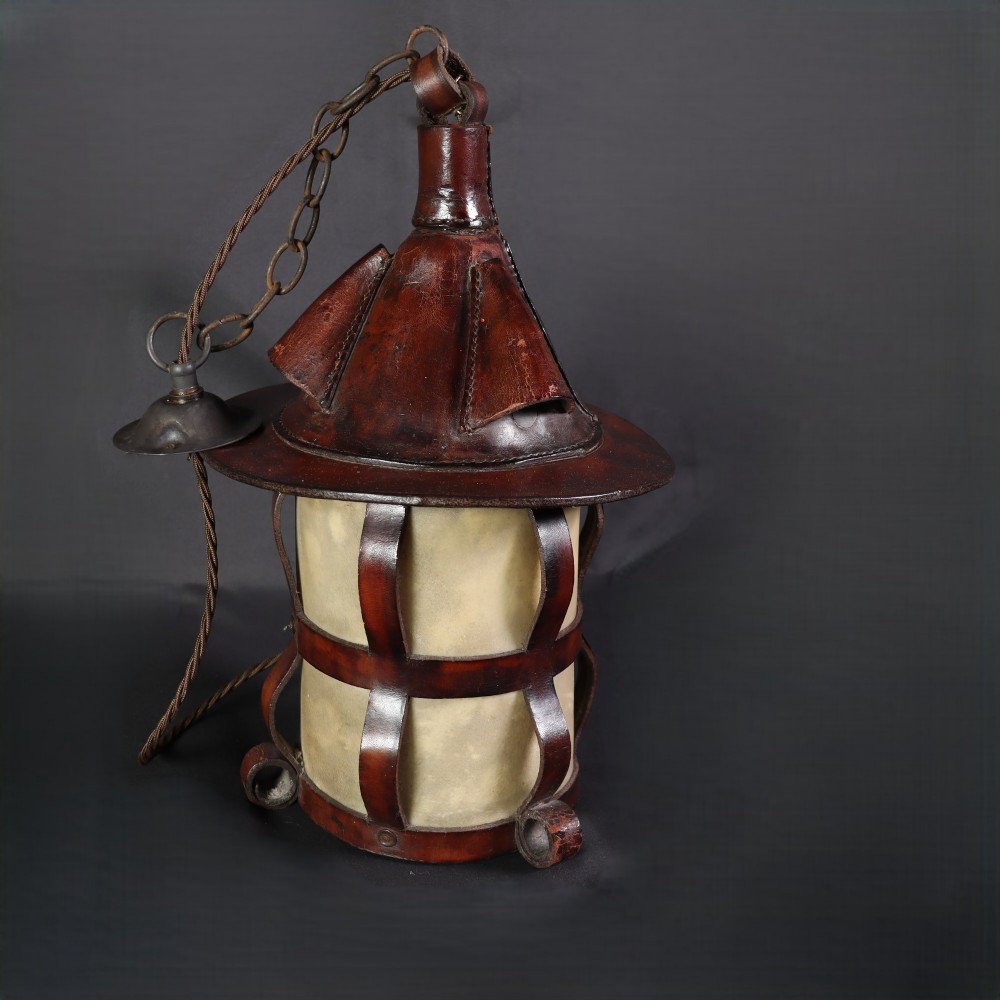 An Arts and Crafts hanging lantern featuring a hand-stitched dark brown leather framework surrounding illuminated vellum panels with scrolled metal feet. View IV